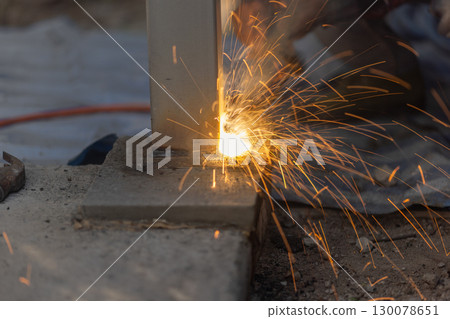 Worker welding steel post in construction site. 130078651