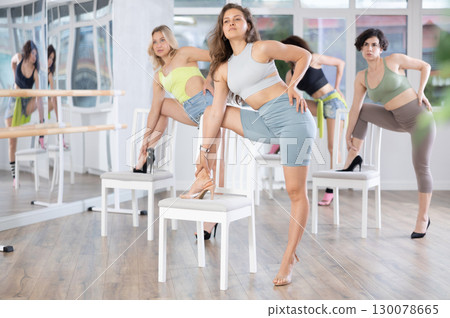 Group of women in high heels rehearsing dance with their feet on chair 130078665