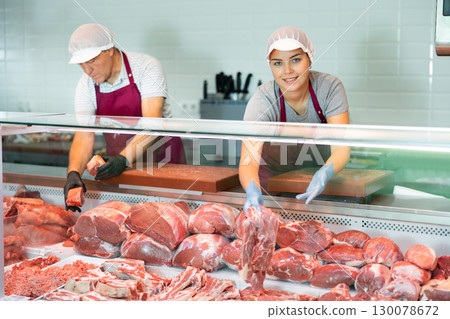 Adult man and young woman sellers lay out beef in butcher shop 130078672