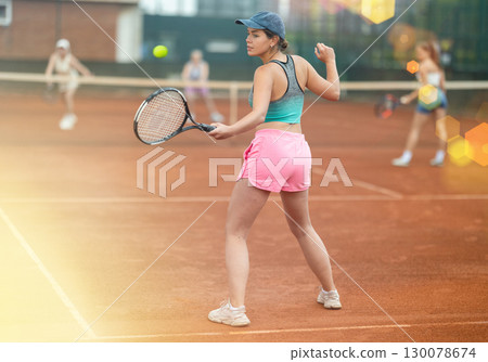 Two young women playing tennis against elderly women 130078674