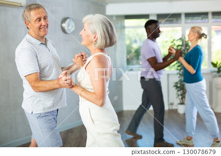 Mature men and women practicing Ballroom dances in training room Mature men and women practicing Ballroom dances in training room 130078679
