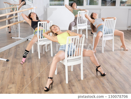 Blonde performing high heels dance on chair during group class 130078706