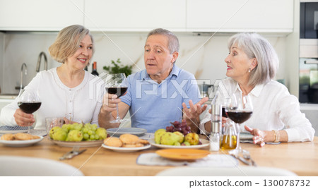Happy women and man gathered at festive table - talking, discussing news and drinking red wine 130078732