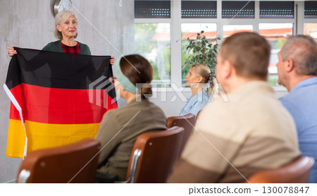 Female tutor showing flag of Germany leading language club for elderly 130078847