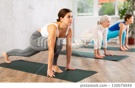 Young focused women doing pilates exercises in yoga studio Young focused women doing pilates exercises in yoga studio 130078848