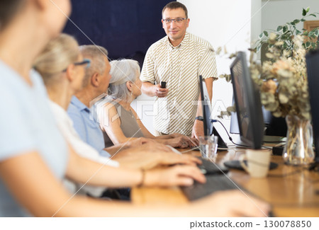 Male teacher teaching elderly people how to use computer Male teacher teaching elderly people how to use computer 130078850