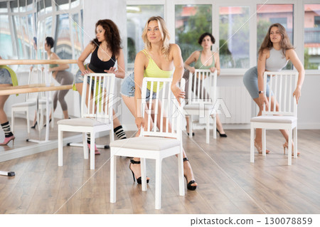 Group of women in high heels rehearsing dance while leaning on chair Group of women in high heels rehearsing dance while leaning on chair 130078859