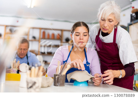 Professional female potter teaches young woman to create pottery 130078889