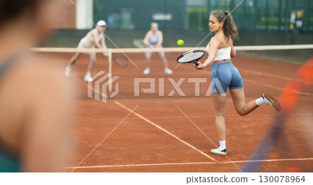 Emotional fit young girl playing doubles tennis on outdoor court Emotional fit young girl playing doubles tennis on outdoor court 130078964