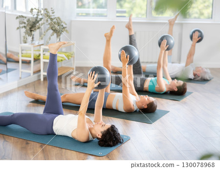 Woman performing single leg circle with ball in Pilates class 130078968