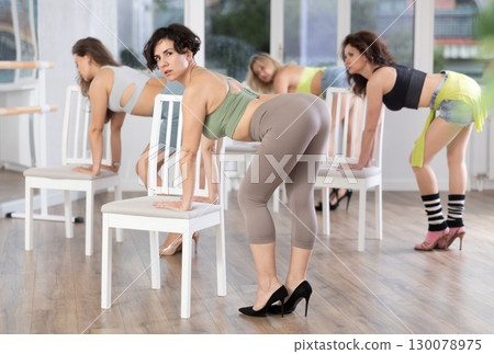 Woman practicing modern stiletto choreography with chair during group class 130078975