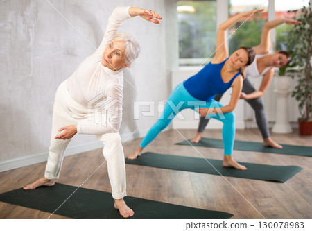 Group of active women practice various yoga poses 130078983