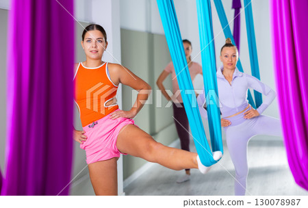 Group of beautiful yoga women doing aerial yoga practice in hammocks in fitness club Group of beautiful yoga women doing aerial yoga practice in hammocks in fitness club 130078987