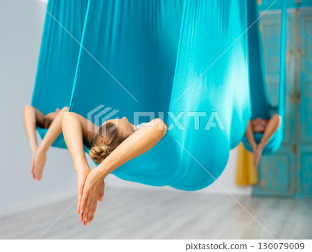 Woman pose in hammock performing aerial yoga or flying yoga 130079009