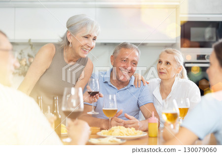 Old men and women talking merrily while having snack in the kitchen Old men and women talking merrily while having snack in the kitchen 130079060