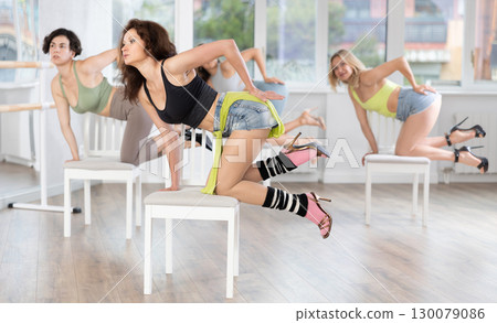 Brunette in heels leading group exotic chair dance class 130079086