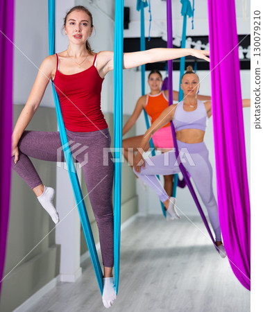 Young pretty slim body fitness girl practicing fly yoga in gym Young pretty slim body fitness girl practicing fly yoga in gym 130079210