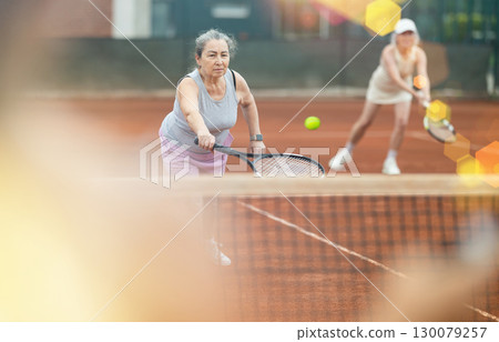 Two elderly women playing doubles tennis Two elderly women playing doubles tennis 130079257