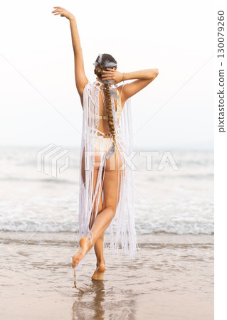 Barefoot girl on seashore in sexy and revealing Amazon tribe carnival costume. 130079260