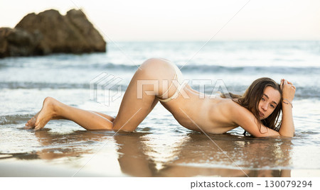 Naked young girl in bikini panties is on knees and elbows. 130079294