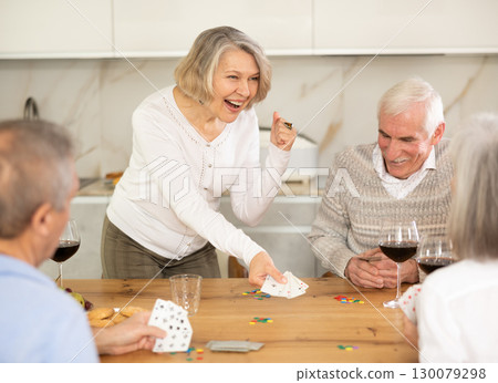 Group of friends playing poker cards and drinking wine at home 130079298