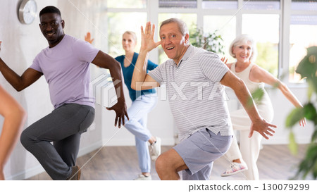 Positive senior man practicing vigorous dance during group class 130079299