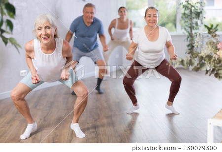 Group of mature sports women and man in activewear exercising dynamic dancing movemens in modern gym studio 130079300