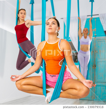Aeroyoga. Woman sits in a anti-gravity yoga hammock in gym Aeroyoga. Woman sits in a anti-gravity yoga hammock in gym 130079318