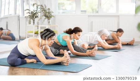 Adult woman doing yoga in group in studio Adult woman doing yoga in group in studio 130079319