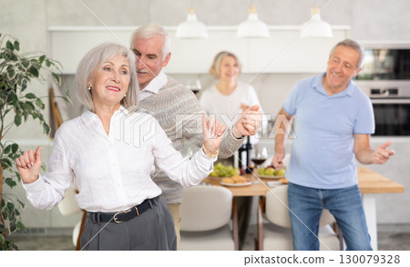 Senior men and women have fun dancing during house party. 130079328