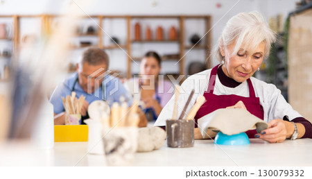 elderly woman is working with billet elderly woman is working with billet 130079332