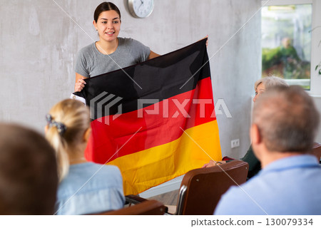 Young female tutor with flag of Germany lecturing in auditorium Young female tutor with flag of Germany lecturing in auditorium 130079334