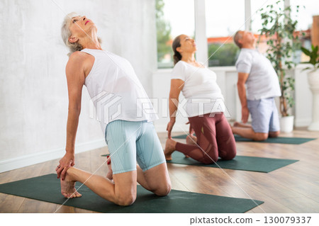 Elderly women doing body stretching in yoga class 130079337