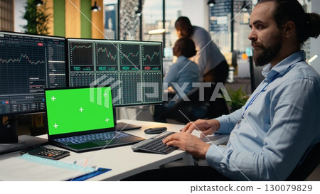 Day trader in brokerage office analyzes stock market charts on isolated screen laptop, making buy and sell decisions. Expert places client orders using trading software on mockup notebook 130079829