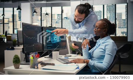 Teamworking proprietary firm colleagues using deep learning to assess stock market volatility. Brokerage company supervisor and african american woman using AI to generate investment reports Teamworking proprietary firm colleagues using deep learning to assess stock market volatility. Brokerage company supervisor and african american woman using AI to generate investment reports 130079903
