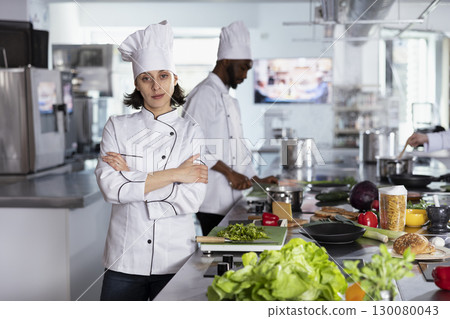 Woman head chef leading her team to cook and prepare delicious gourmet food, working in a restaurant kitchen with professional equipment and tools. Female cook with culinary career. Woman head chef leading her team to cook and prepare delicious gourmet food, working in a restaurant kitchen with professional equipment and tools. Female cook with culinary career. 130080043