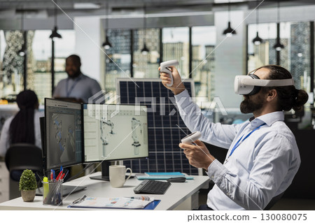 Engineer in office using VR headset to design solar panel cells with reduced carbon footprint. RD expert uses virtual reality simulation to develop robotic arm systems for solar panel production 130080075