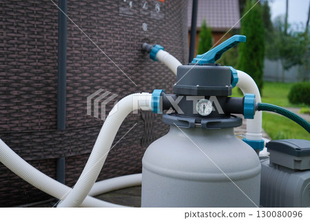 A filtration system for a backyard pool, powered by a pump, situated outdoors on a hot, sunny summer afternoon. 130080096