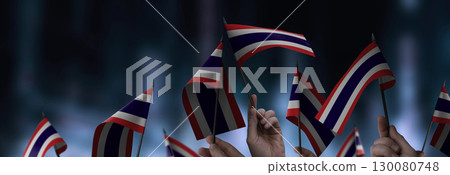 Thailand flags in their hands on a blurred urban background Thailand flags in their hands on a blurred urban background 130080748