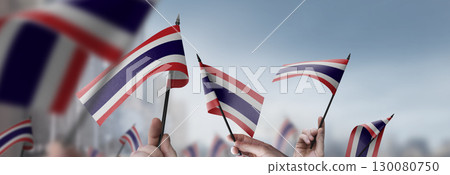 Thailand flags in their hands on a blurred urban background 130080750