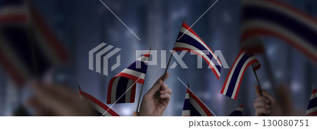 Thailand flags in their hands on a blurred urban background 130080751
