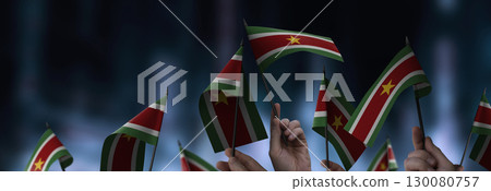 Suriname flags in their hands on a blurred urban background 130080757