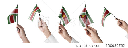 The Suriname flag in hand in different angles on a white background 130080762