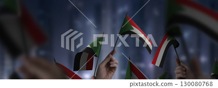 Sudan flags in their hands on a blurred urban background 130080768