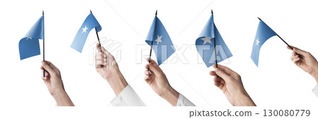 The Somalia flag in hand in different angles on a white background 130080779