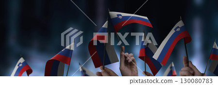 Slovenia flags in their hands on a blurred urban background Slovenia flags in their hands on a blurred urban background 130080783