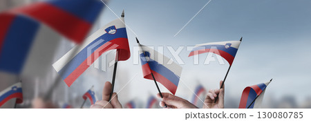 Slovenia flags in their hands on a blurred urban background Slovenia flags in their hands on a blurred urban background 130080785