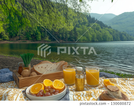 Enjoying a serene picnic by the lake with fresh fruits and drinks during the afternoon 130080872