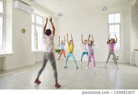 Group of children with help of trainer practice energetic dance moves in choreography class. 130081007