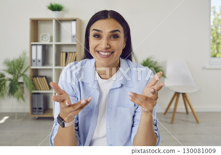 Young brunette woman sitting at home looking at the camera having online video call. Young brunette woman sitting at home looking at the camera having online video call. 130081009